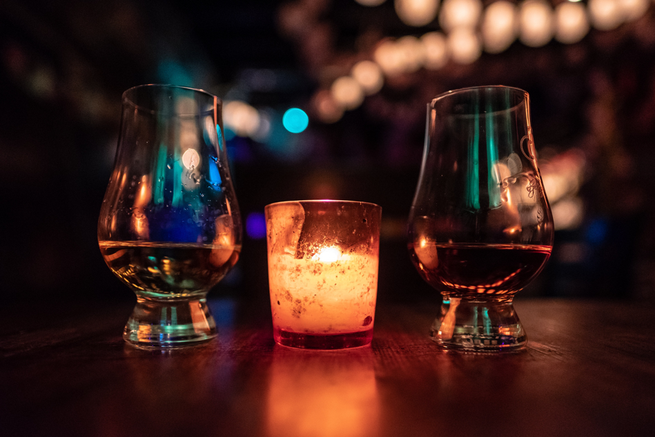 Two glasses of whisky with a candle