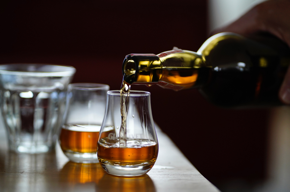 Two glasses of whisky being poured from the bottle