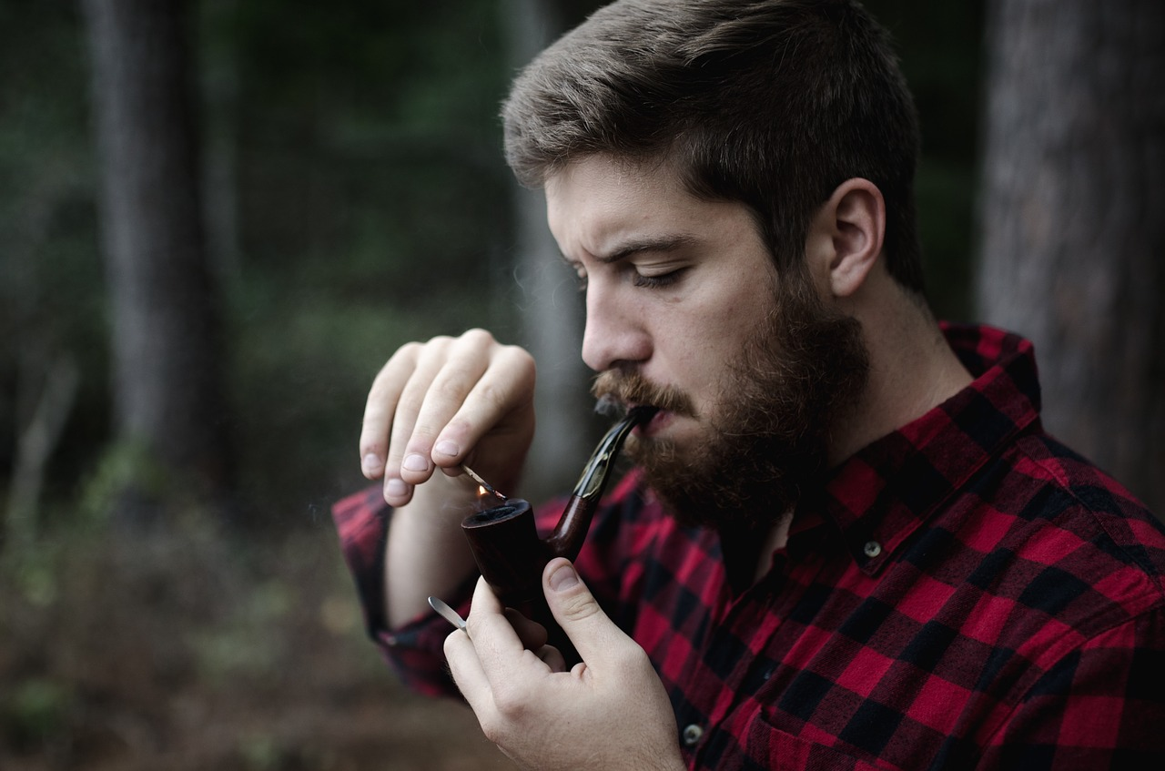 A man lighting a pipe outside