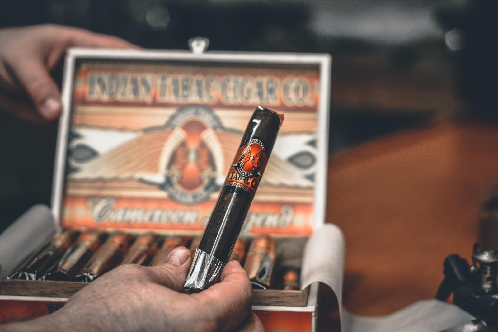 A hand holding a cellophaned cigar