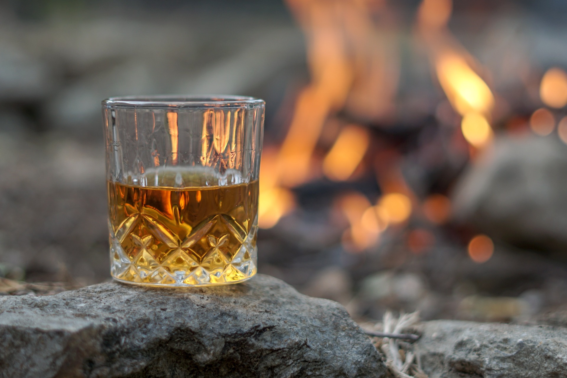A glass of whisky in front of a fire