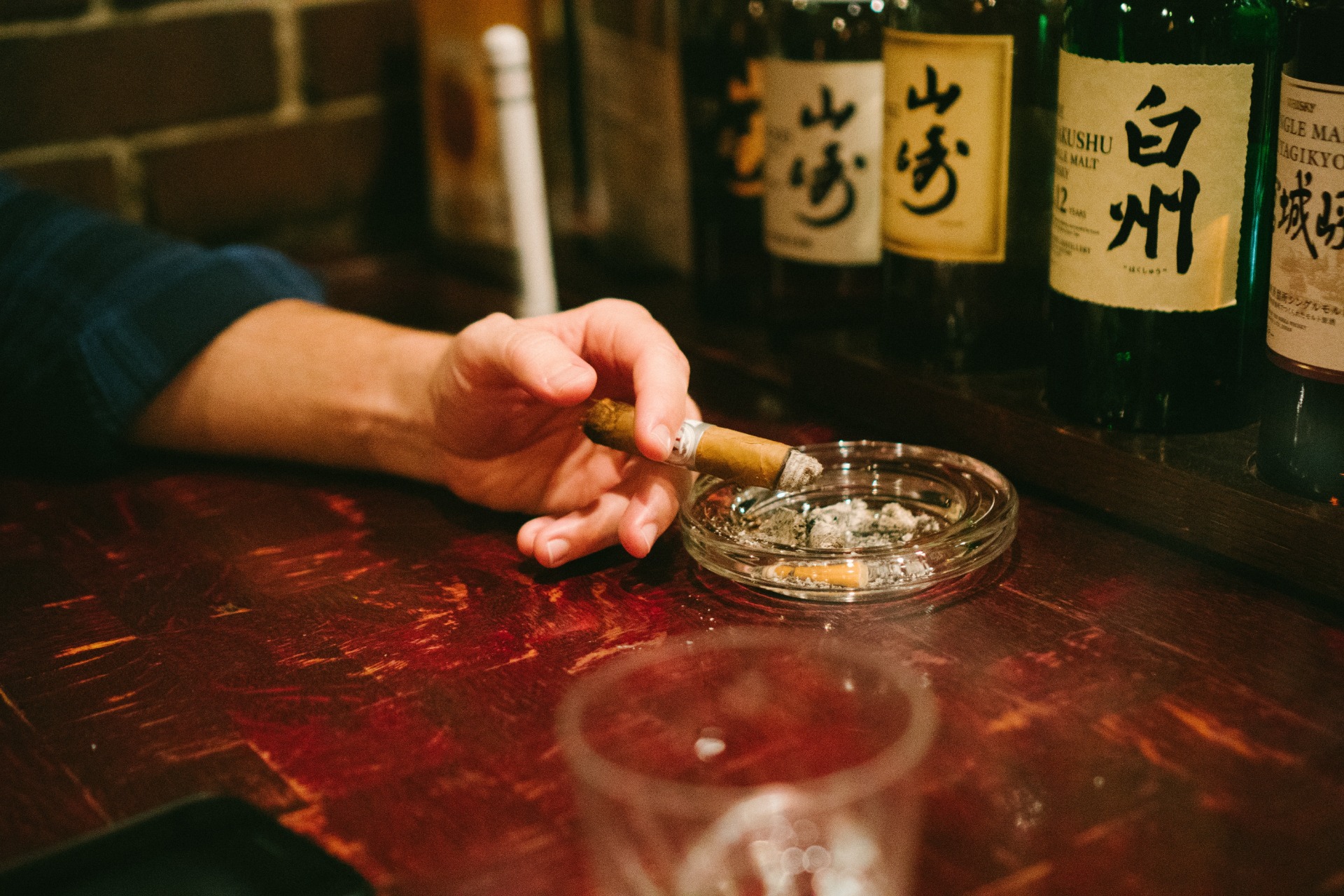 A cigar and an ashtray on a bar