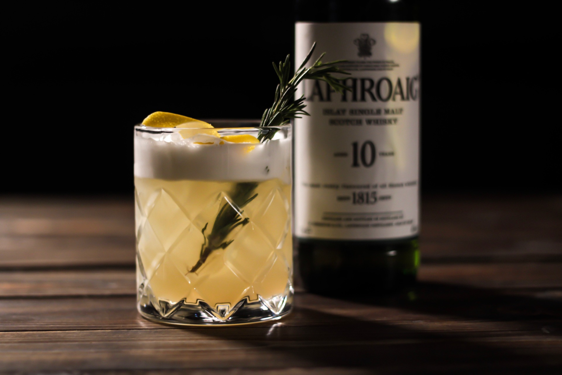 A cocktail of Laphroaig with a bottle in the background