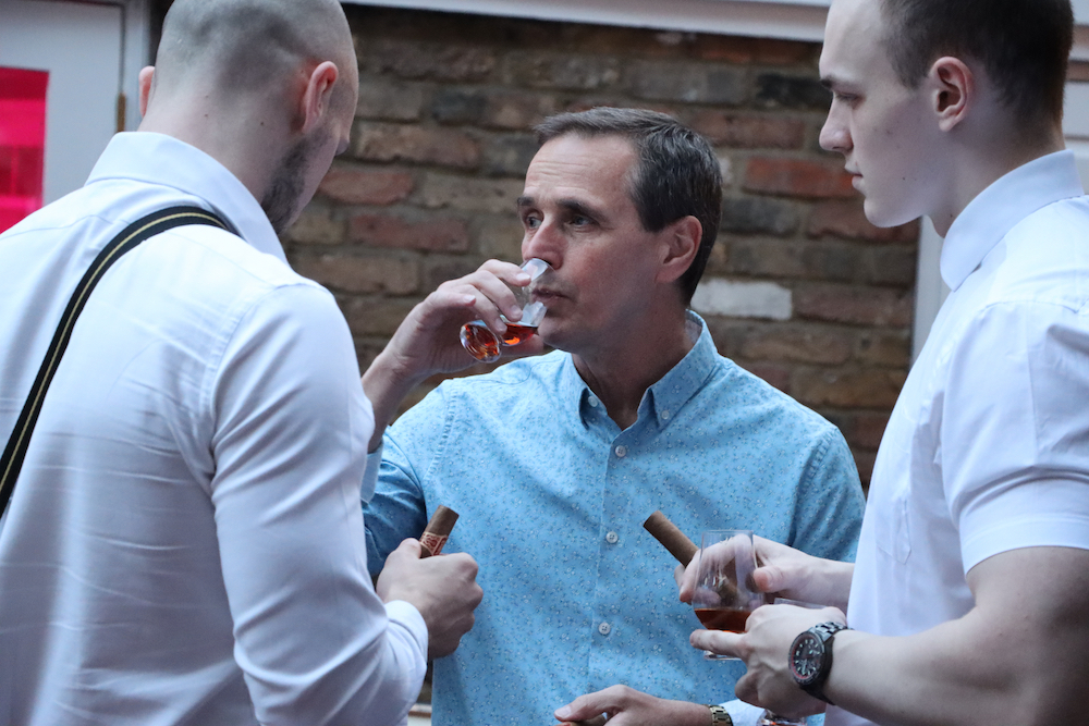 Three men holding cigars and drinking rum
