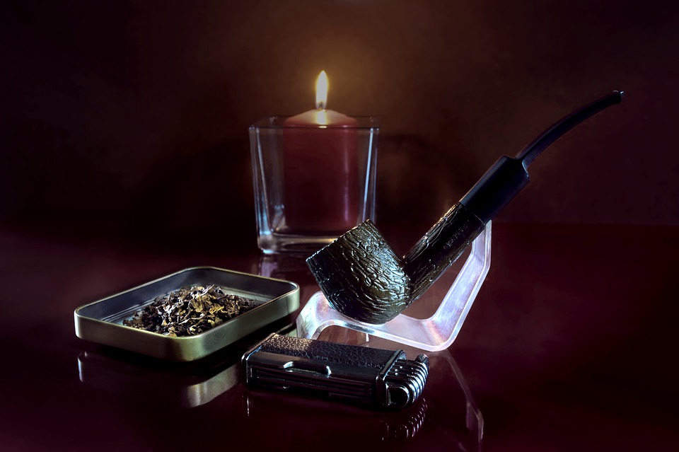 A pipe, a lighter and a tin of pipe tobacco on a table