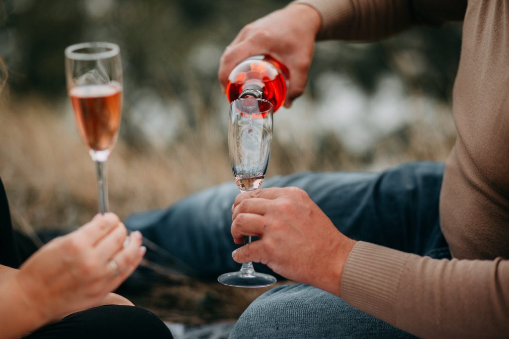 man pouring rose wine into a wine glass