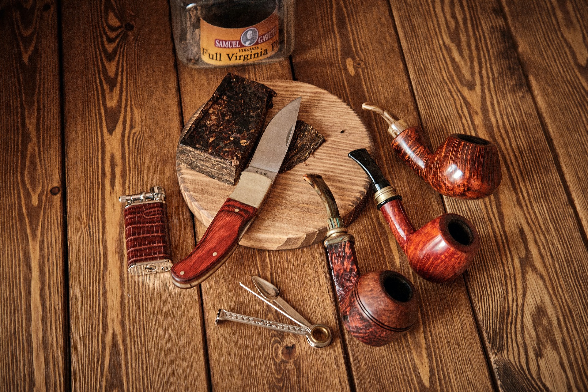 Pipes, a tin of tobacco and a lighter on a wooden surface
