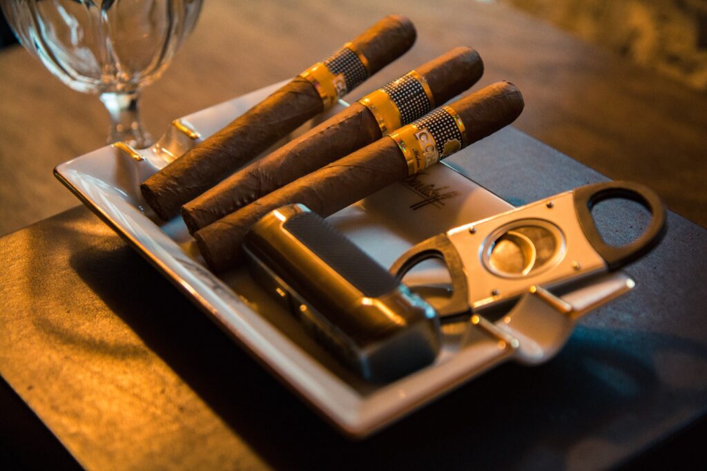 Three cigars, a cigar cutter and a lighter in an ashtray