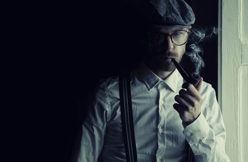 a man in a flat cap smoking a pipe