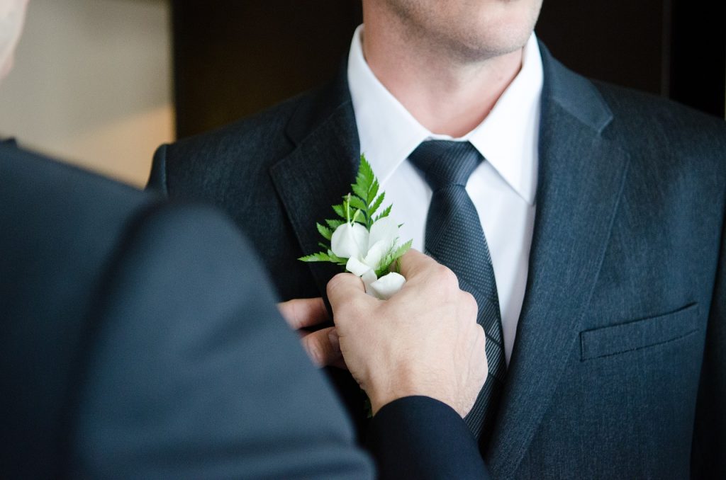 A best man pinning a flower to the groom on his wedding day