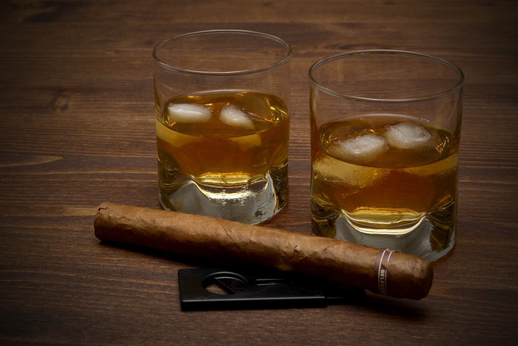 Two glasses of whisky with cigar and cigar cutter